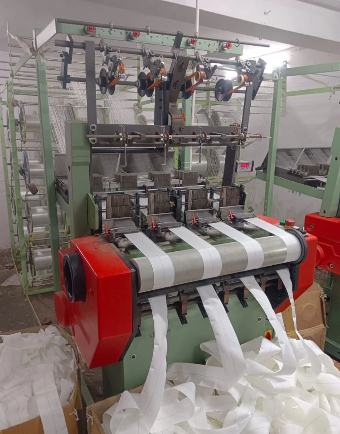 Narrow fabric needle loom weaving cotton and nylon tape in manufacturing facility